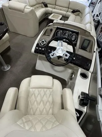 Slide: The Image of 2013 Bennington 2575 R boat interior with beige seating and modern dashboard. - 26