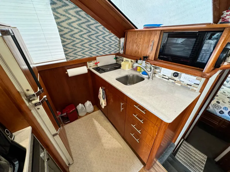 Slide: The Image of Compact kitchen area in a 1993 Ocean Yachts 42 Super Sport boat, featuring wood cabinetry and modern appliances. - 15