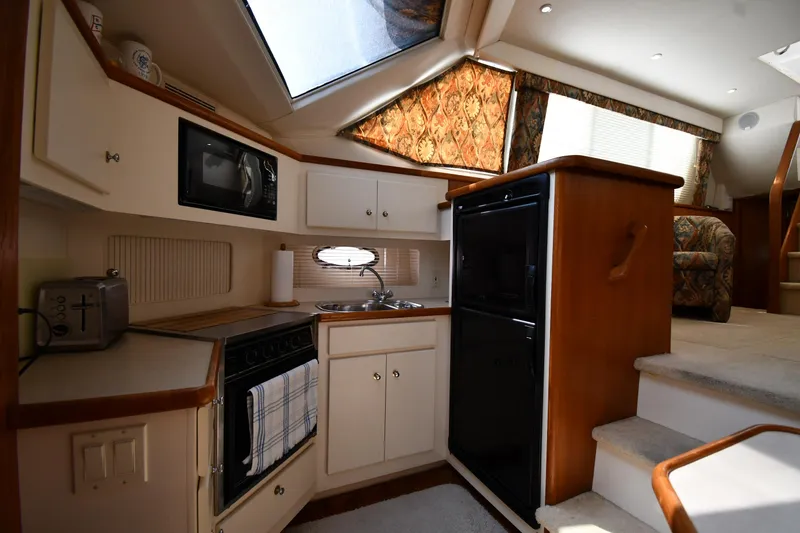 Slide: The Image of 1997 Carver 405 Motor Yacht kitchen with appliances, wood cabinetry, and natural light. - 47
