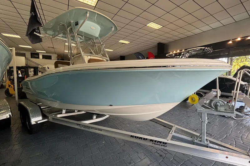 Slide: The Image of 2024 Pioneer 202 Islander boat in showroom, light blue hull on trailer. - 1