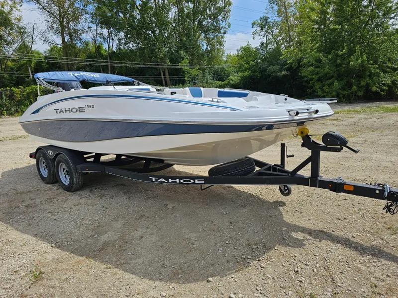 Slide: The Image of 2024 Tahoe 1950 boat on trailer, parked outdoors, surrounded by trees. - 0