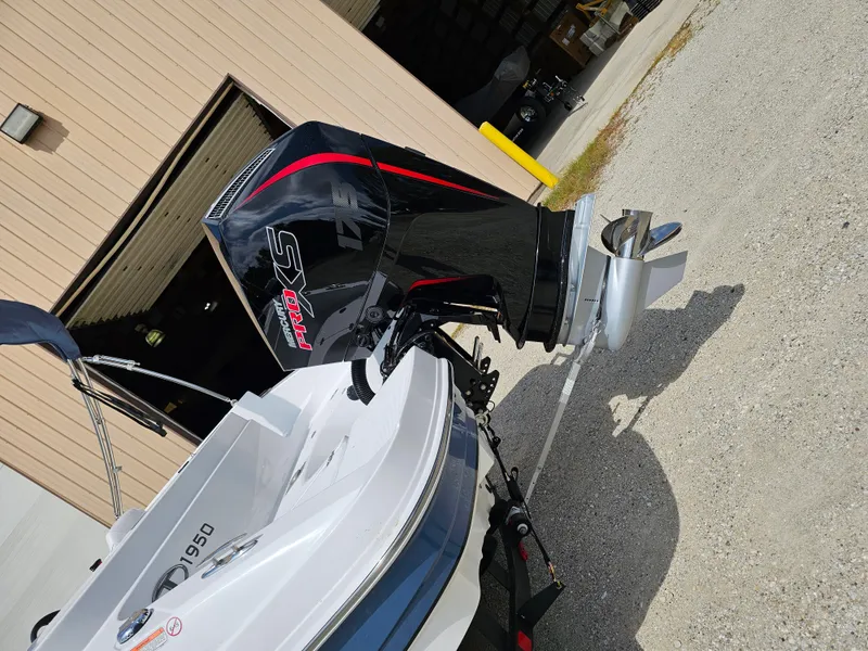 Slide: The Image of 2024 Tahoe 1950 boat with powerful outboard motor, parked outside a garage. - 2