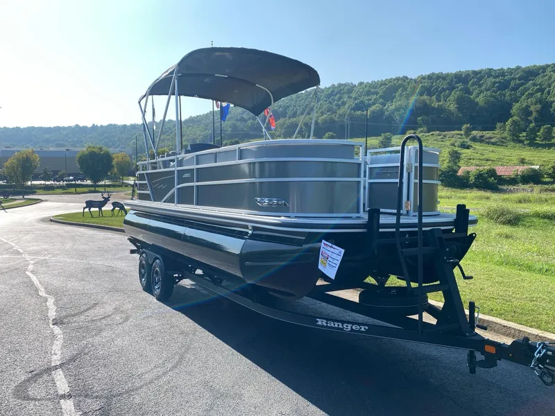 Slide: The Image of 2024 Ranger Reata 223C pontoon boat on trailer, parked outdoors. - 3