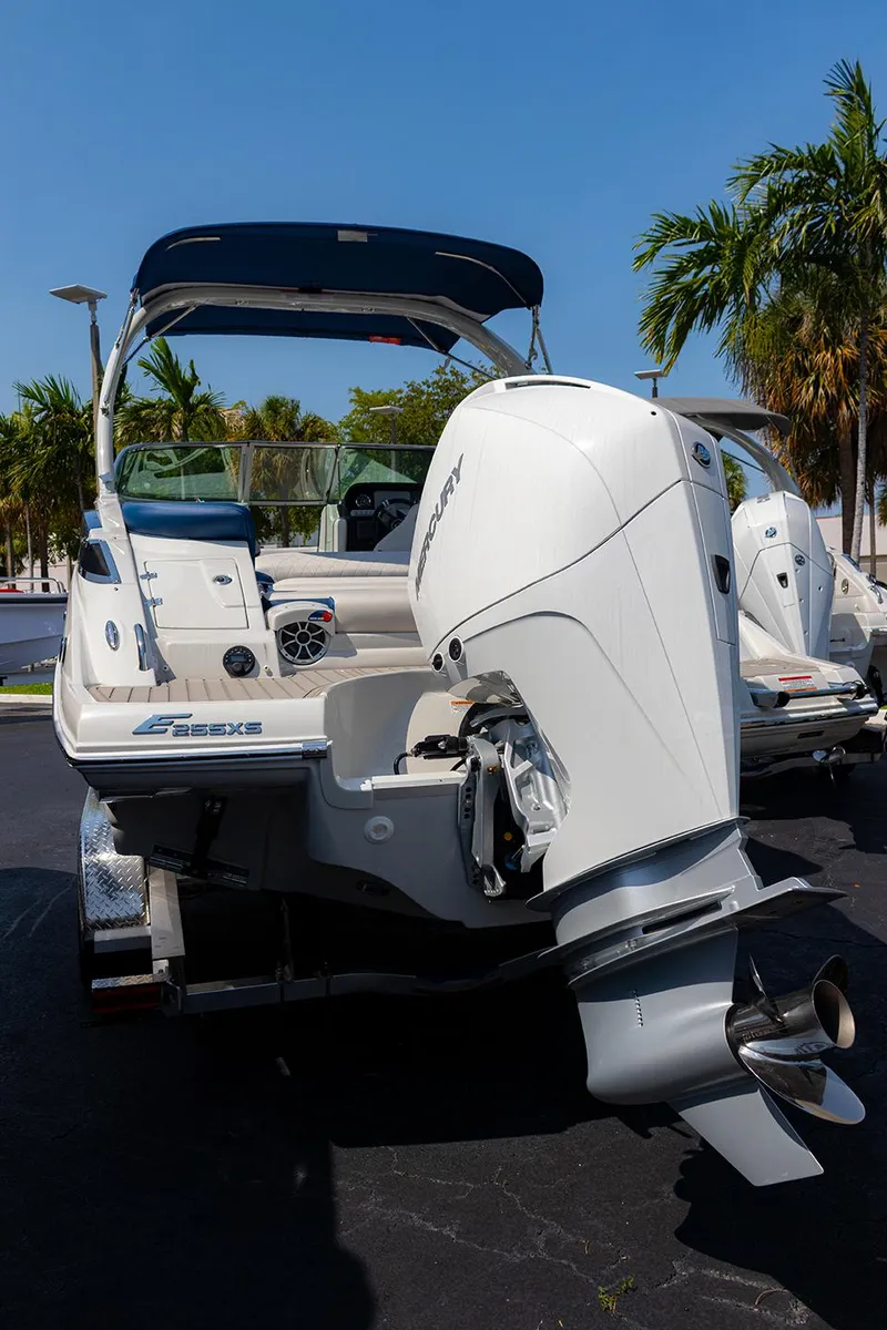 Slide: The Image of 2022 Crownline E 255 XS boat with outboard motor, parked under clear blue sky. - 2