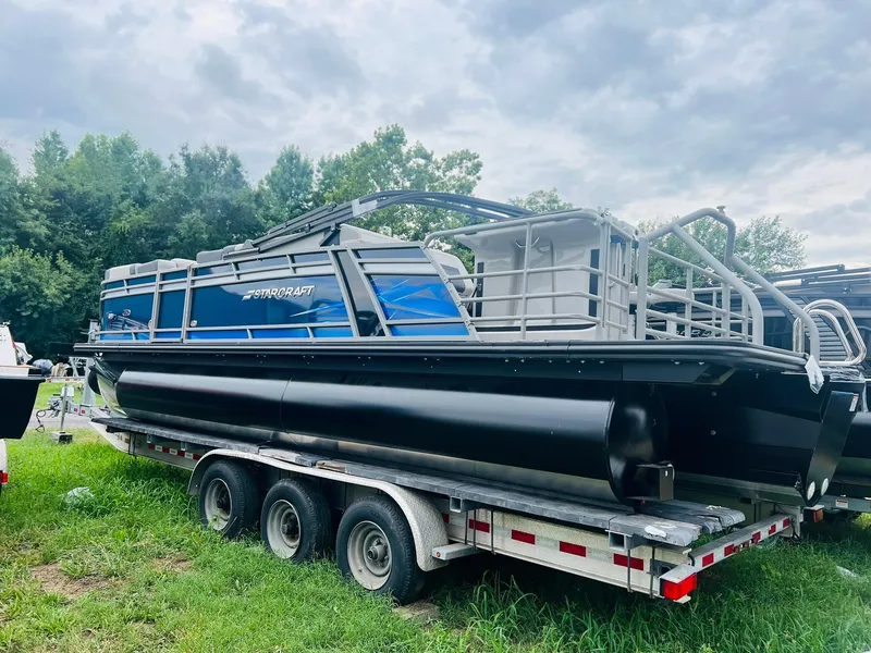 Slide: The Image of 2025 Starcraft CX 23 DL BAR pontoon boat on trailer, parked on grass. - 14