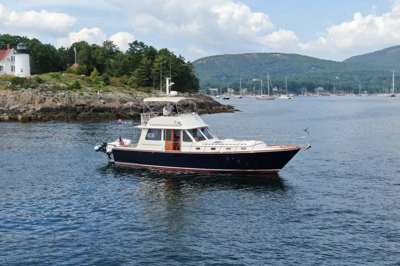 Slide: The Image of 1997 Lyman-Morse Custom Flybridge yacht cruising near rocky shoreline and lighthouse. - 3