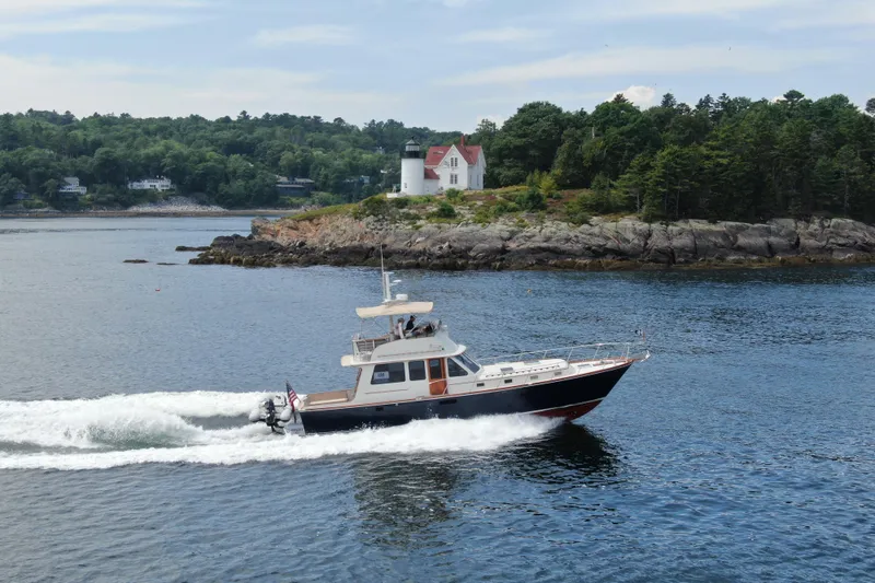Slide: The Image of 1997 Lyman-Morse Custom Flybridge cruising near a scenic lighthouse and rocky shoreline. - 5