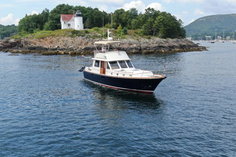 Slide: The Image of 1997 Lyman-Morse Custom Flybridge yacht near rocky shoreline with lighthouse in background. - 7