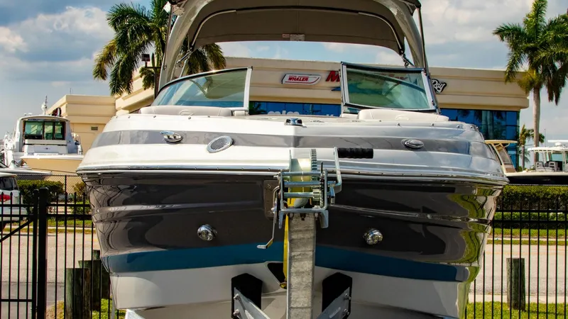 Slide: The Image of 2023 Crownline 290 XSS boat on trailer, displayed outdoors with palm trees. - 1