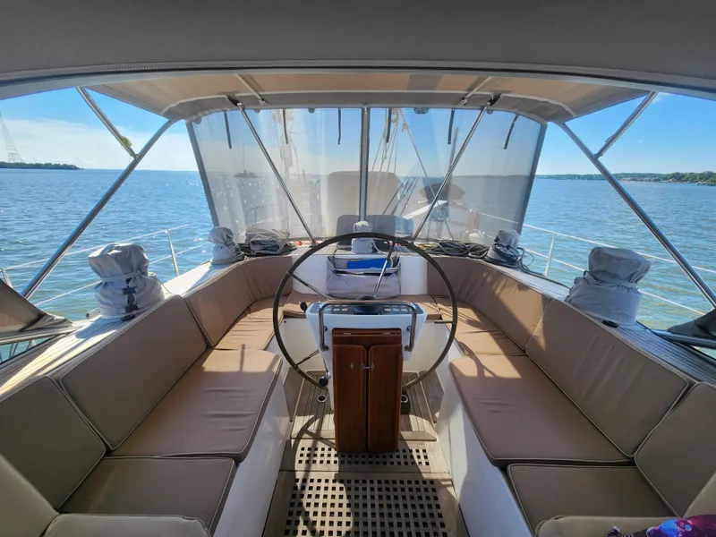 Slide: The Image of 2008 Hallberg-Rassy 62 yacht cockpit with steering wheel, beige seating, and ocean view. - 22