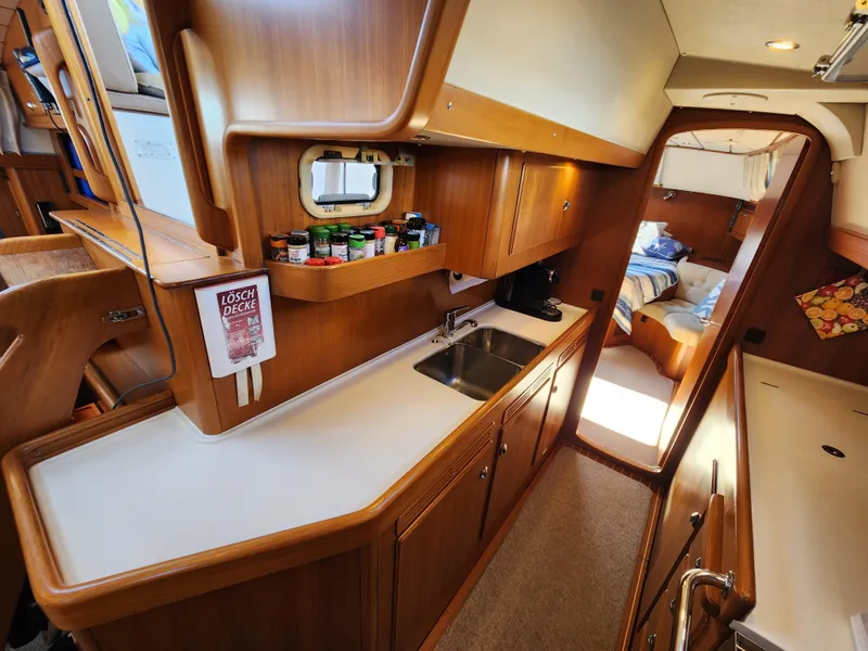 Slide: The Image of Interior of 2008 Hallberg-Rassy 62 yacht, featuring a wooden kitchen and cozy cabin. - 37