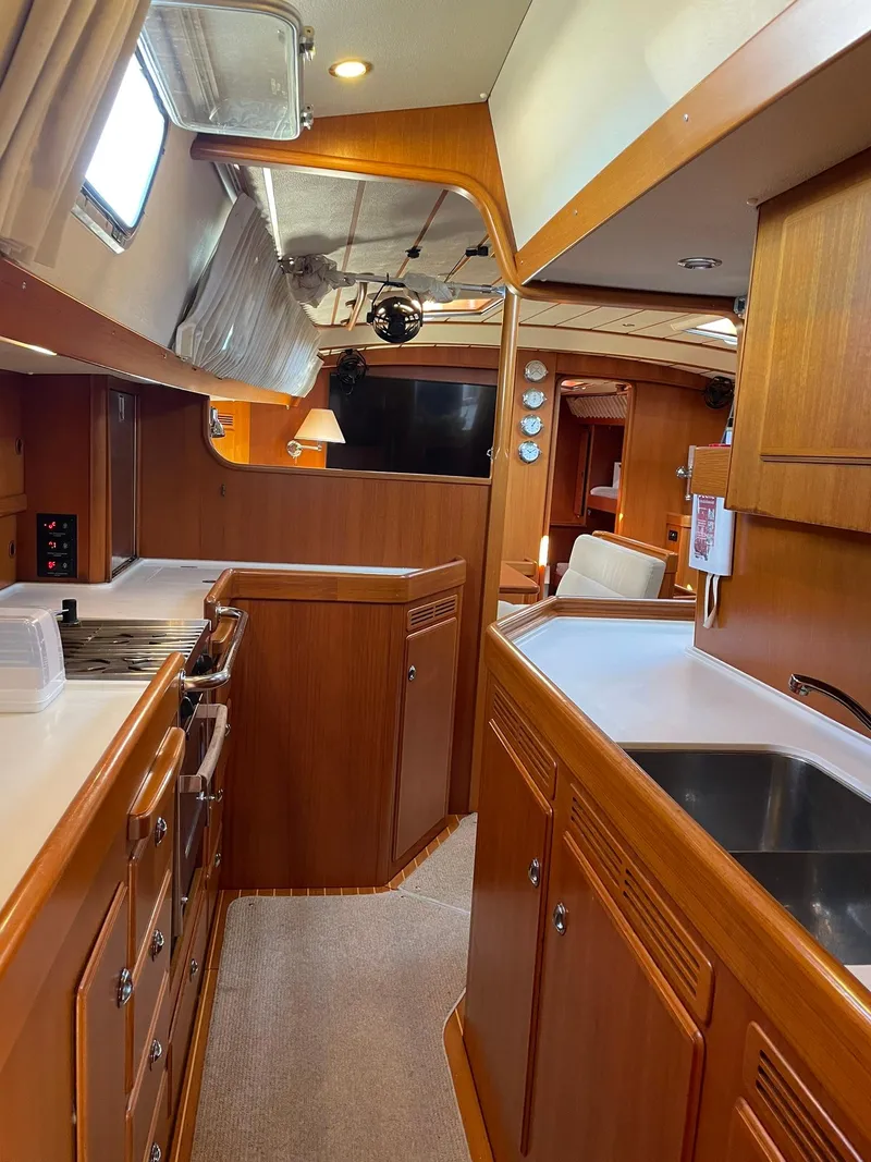 Slide: The Image of Interior of 2008 Hallberg-Rassy 62 yacht, featuring a well-equipped kitchen and wooden cabinetry. - 38