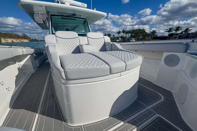 Slide: The Image of 2024 HCB 53' Suenos luxury boat interior with quilted seating, docked by palm trees. - 32
