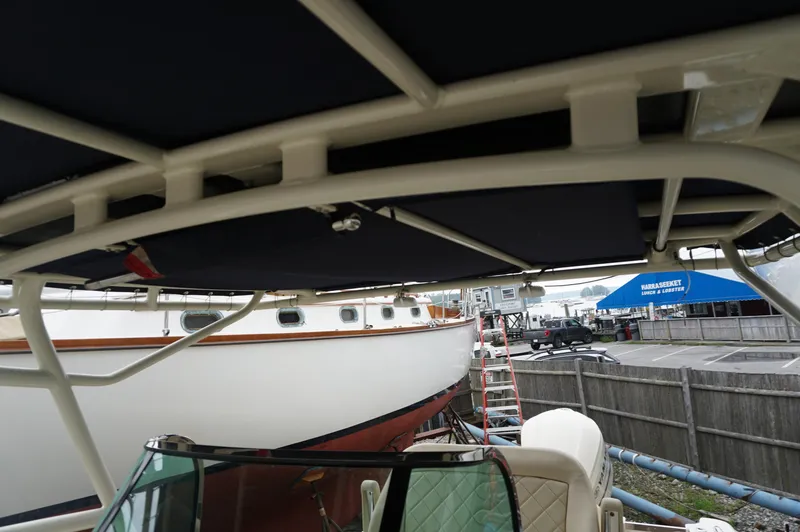 Slide: The Image of 2018 Chris-Craft Catalina 26 boat under canopy, docked near a marina with other vessels. - 6