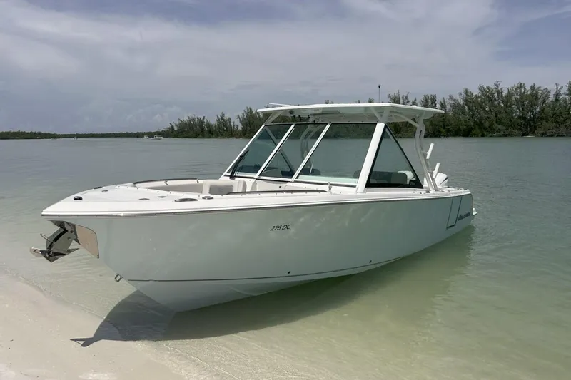 Slide: The Image of 2025 Sailfish 276 DC boat anchored on a sandy beach with clear water. - 17