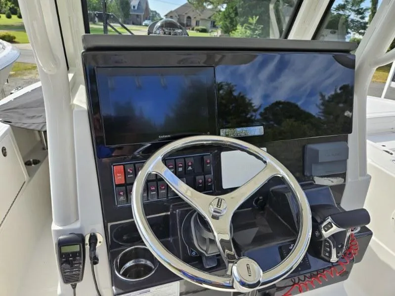 Slide: The Image of 2024 Pursuit S 248 Sport boat dashboard with steering wheel and navigation controls. - 11
