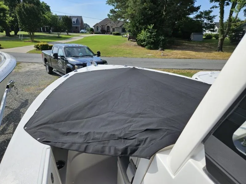 Slide: The Image of 2024 Pursuit S 248 Sport boat with black cover, parked outdoors. - 13