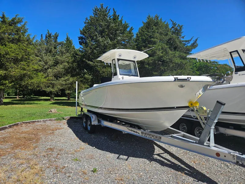 Slide: The Image of 2024 Pursuit S 248 Sport boat on trailer, parked outdoors. - 2