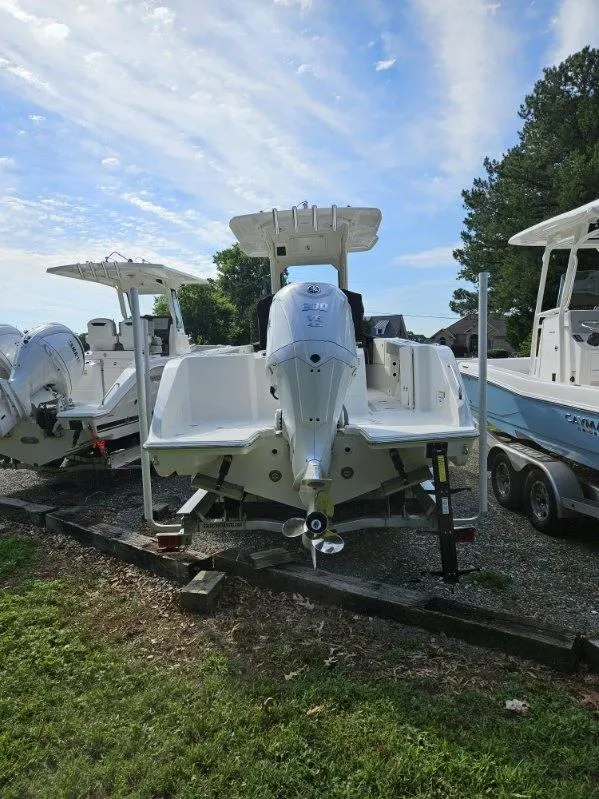 Slide: The Image of 2024 Pursuit S 248 Sport boat with outboard motor, parked on gravel lot. - 5