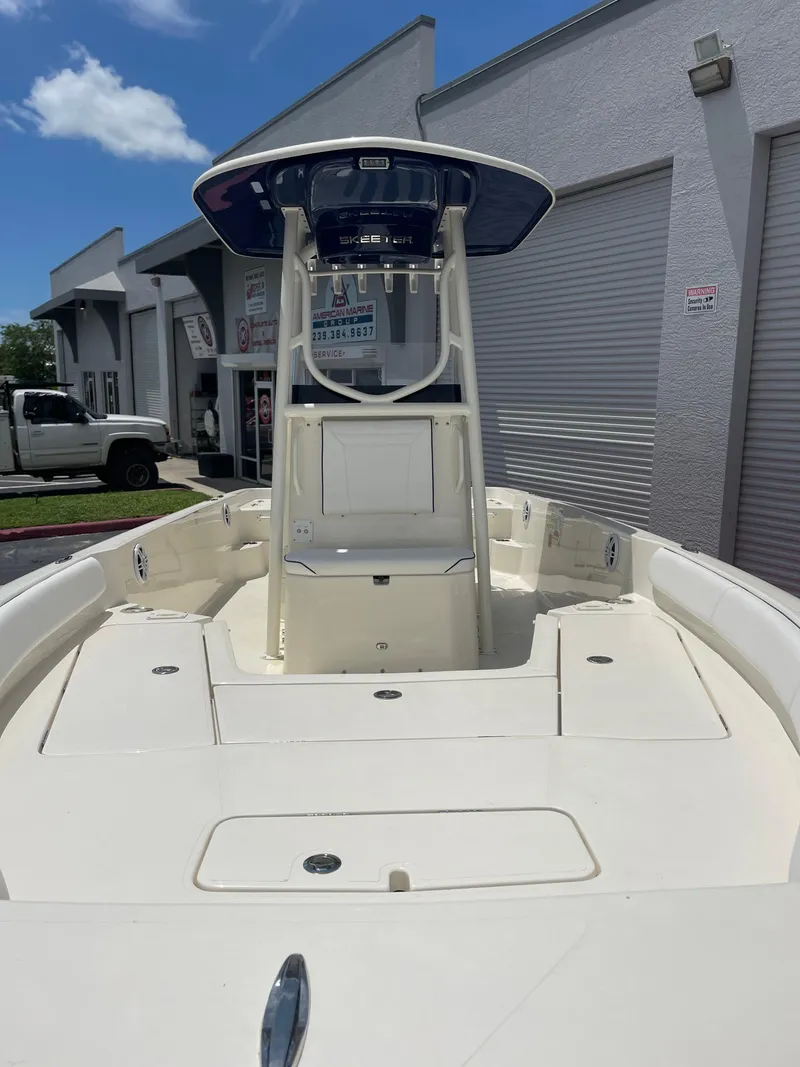 Slide: The Image of 2024 Skeeter SX 2350 boat with T-top, docked near a building under a clear sky. - 2