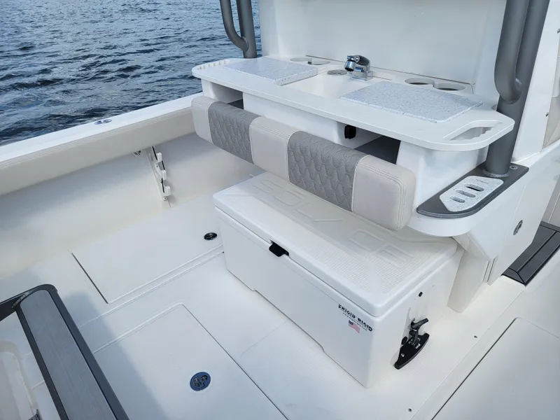 Slide: The Image of Solace 30 HCS 2025 boat interior with seating and storage, on calm water. - 8