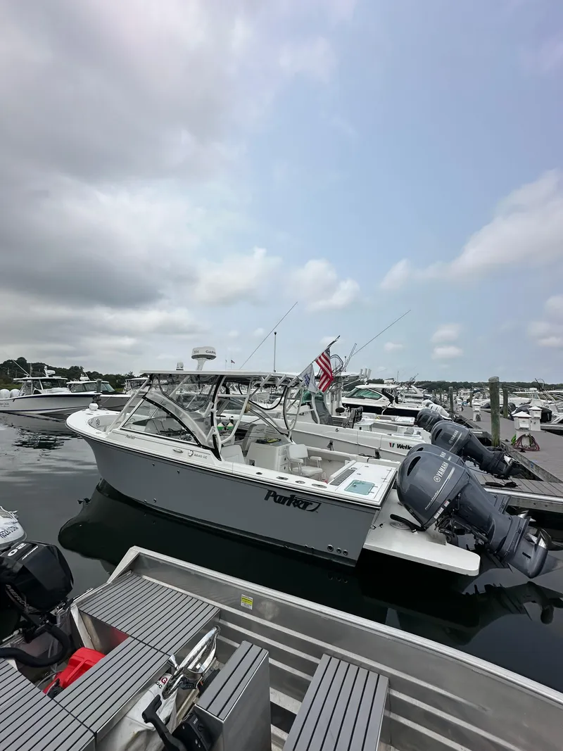 Slide: The Image of 2021 Parker 2540 DC boat docked at marina under cloudy sky. - 0
