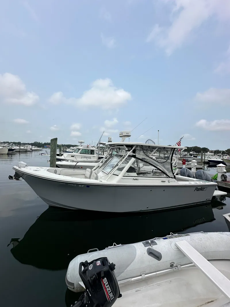 Slide: The Image of 2021 Parker 2540 DC boat docked in a marina under a cloudy sky. - 1