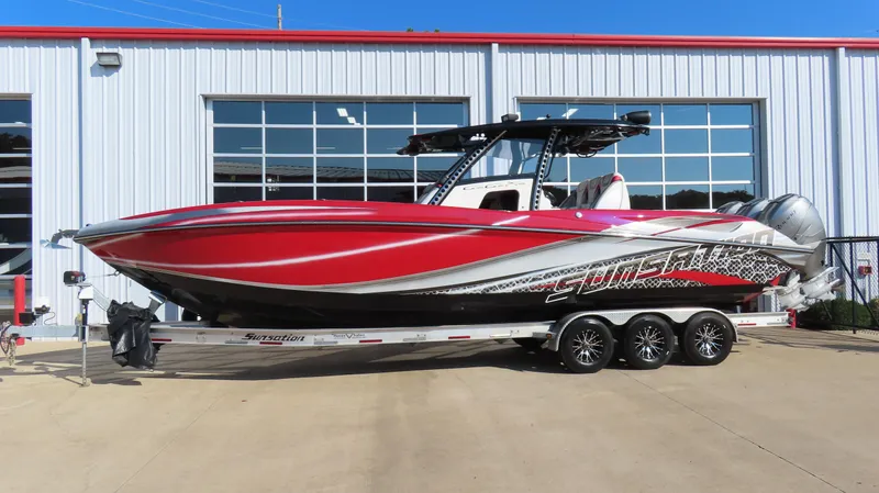 The Image of 2014 Sunsation 34 CCX boat in vibrant red on a trailer outside a garage. - 0