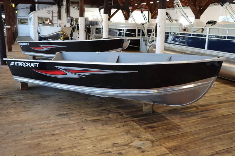 Slide: The Image of 2025 Starcraft 14 SF TS SS boat displayed in a showroom, featuring sleek black design. - 1
