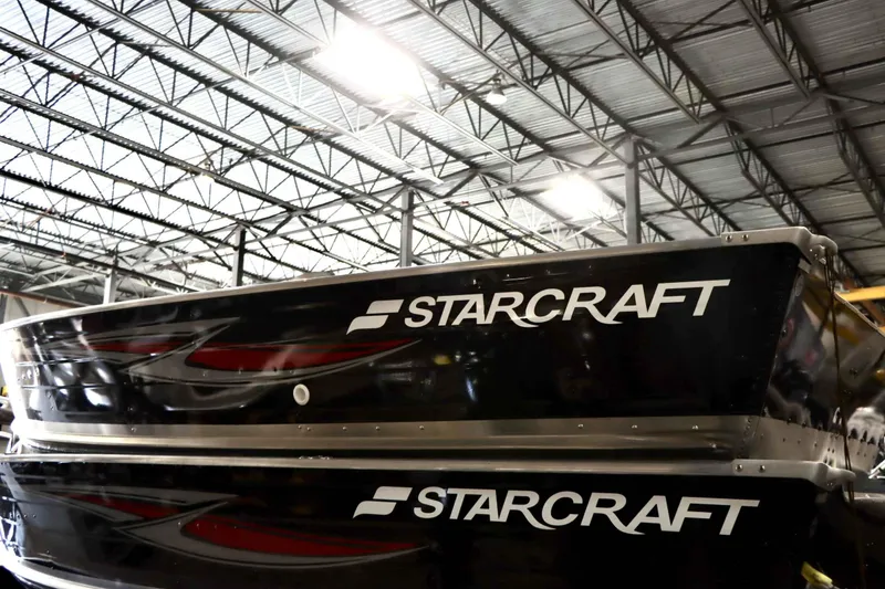 Slide: The Image of 2025 Starcraft 14 SF DLX TL boat in warehouse, showcasing sleek design and branding. - 3