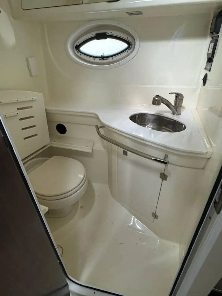 Slide: The Image of 2016 Monterey 355SY boat bathroom with sink, toilet, and porthole window. - 16