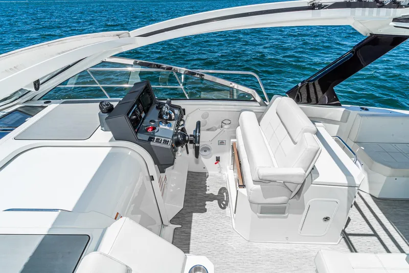 Slide: The Image of 2017 Cruisers Yachts 390 Express Coupe helm with luxurious seating and controls, on blue water. - 28