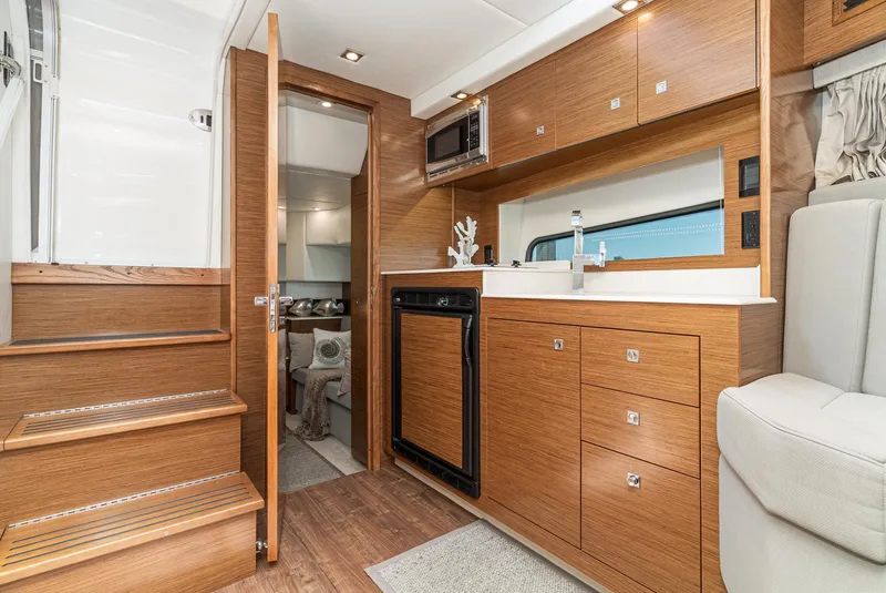 Slide: The Image of Interior of 2017 Cruisers Yachts 390 Express Coupe, featuring modern kitchen and wooden cabinetry. - 32