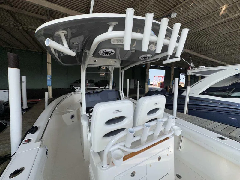 Slide: The Image of 2022 Cobia 280 Center Console boat with rod holders and seating in a marina. - 10