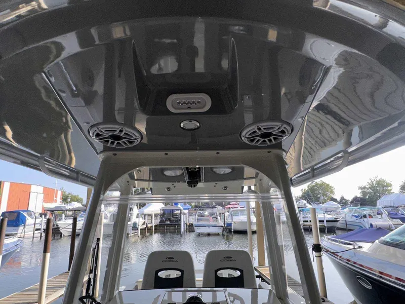 Slide: The Image of 2022 Cobia 280 Center Console boat interior at marina, featuring speakers and seating. - 11