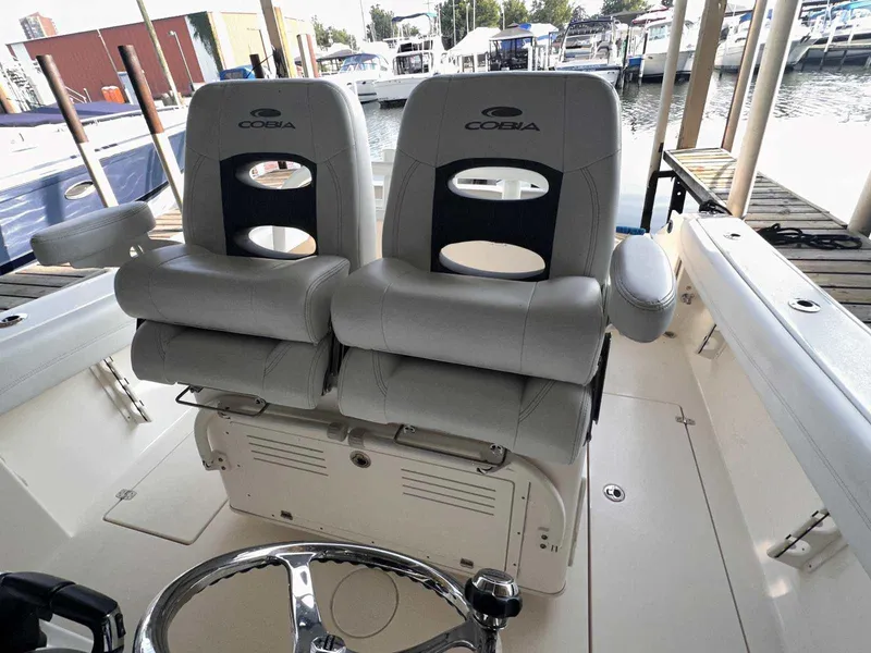Slide: The Image of 2022 Cobia 280 Center Console boat with dual cushioned seats at the helm. - 14