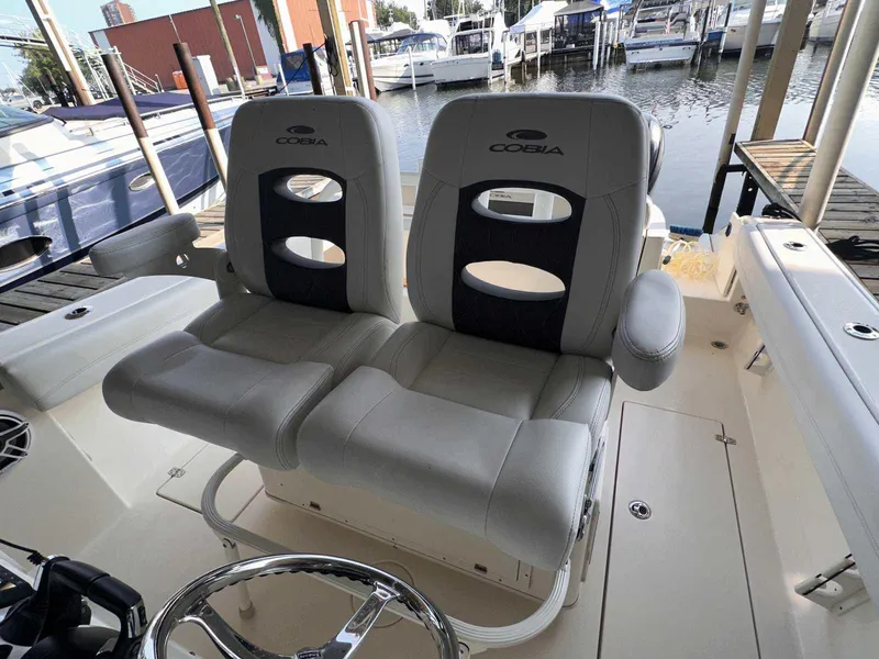 Slide: The Image of 2022 Cobia 280 Center Console boat seats at marina dock. - 15