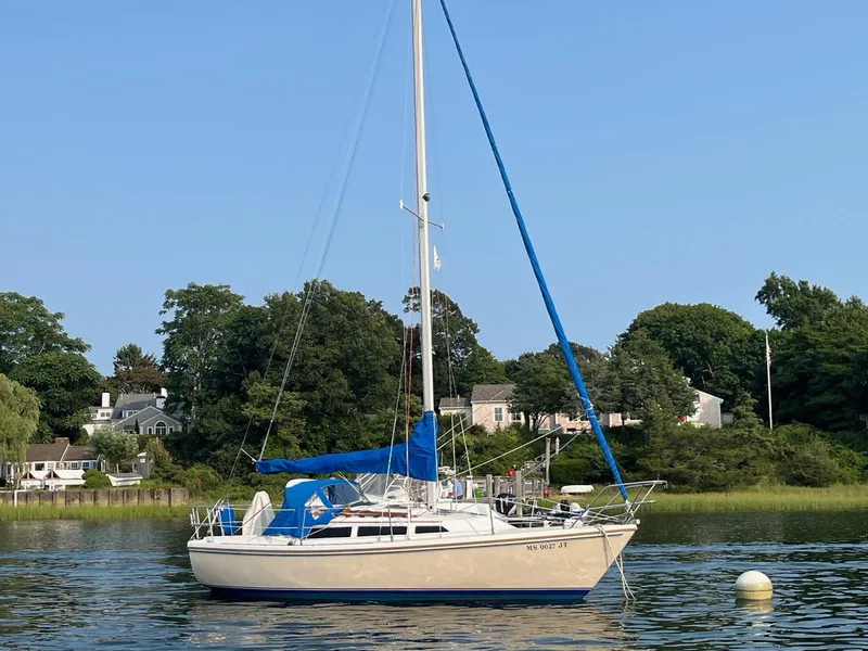 Slide: The Image of 1985 Catalina sailboat anchored on a calm lake with scenic background. - 4