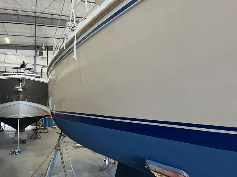 Slide: The Image of 1985 Catalina sailboat in a boatyard, hull with blue stripe, indoor storage. - 6