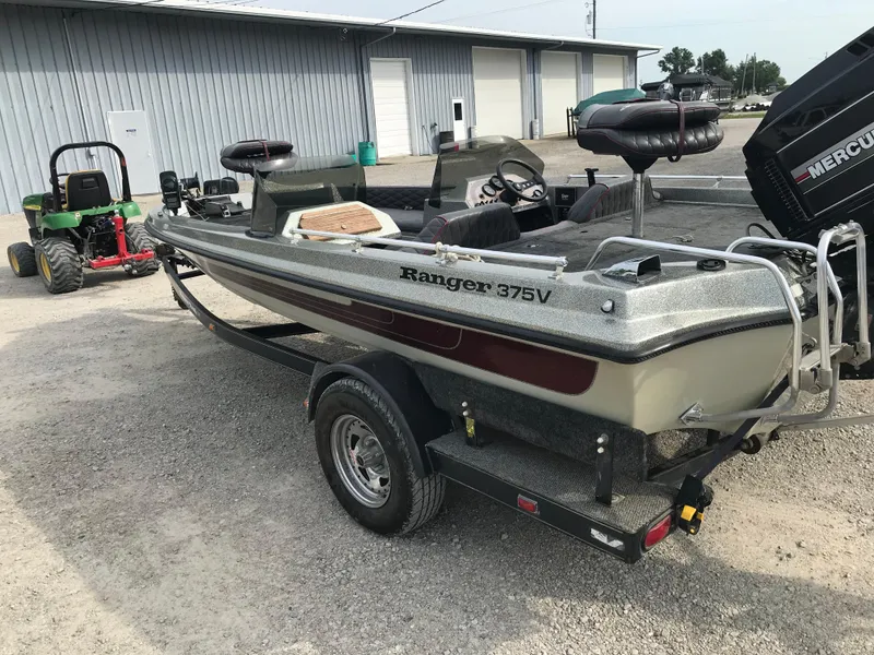 Slide: The Image of 1990 Ranger 375V fishing boat on trailer, parked near a metal building. - 6