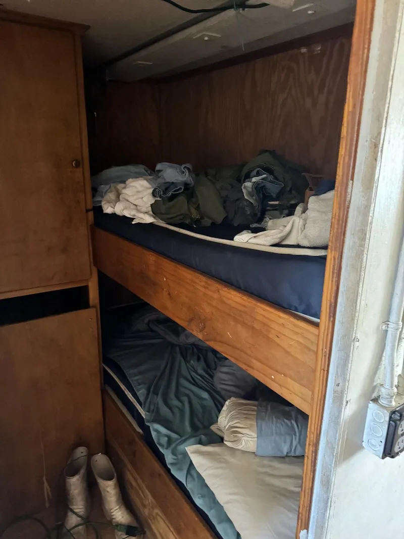 Slide: The Image of Interior of 1971 Butterfish Fishing Trawler with wooden bunk beds and clothing. - 12
