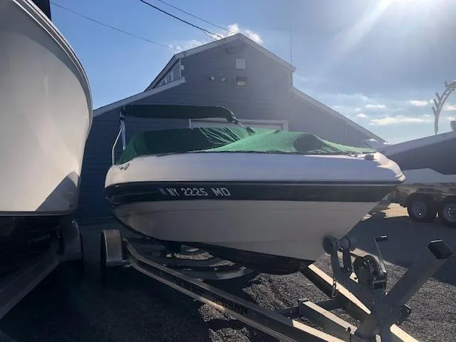 Slide: The Image of 2005 Four Winns 180 Horizon LE boat on trailer, covered, parked near a building. - 13