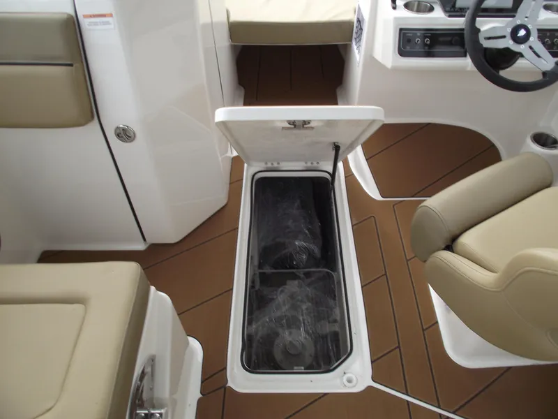 Slide: The Image of 2025 Bayliner D22 boat interior with open storage compartment, beige seating, and brown flooring. - 16