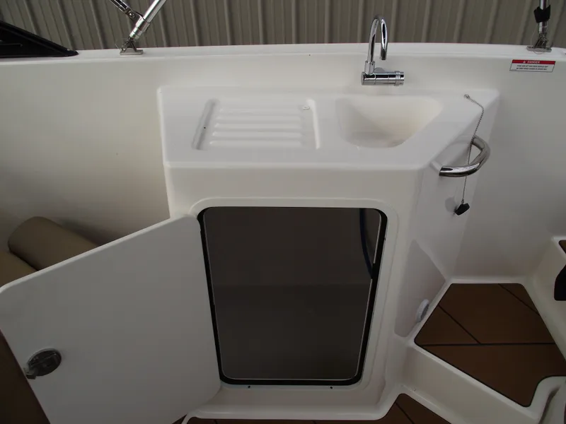 Slide: The Image of 2025 Bayliner D22 boat sink and storage area with open cabinet door. - 18