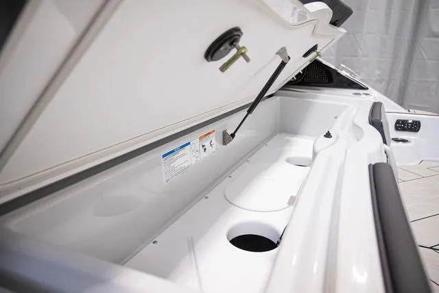 Slide: The Image of 2024 Yamaha Boats 255XE storage compartment with open lid and cup holders. - 21