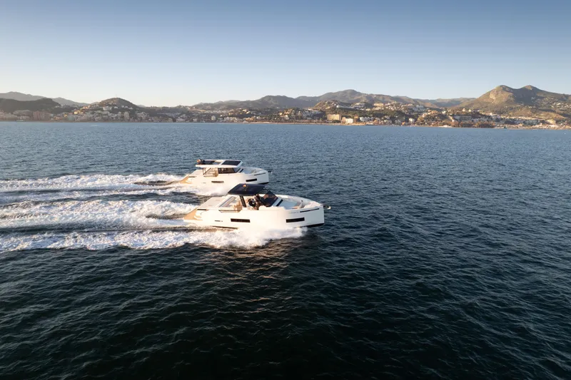 Slide: The Image of 2025 De Antonio Yachts D50 Coupé cruising on open water with scenic mountain backdrop. - 11