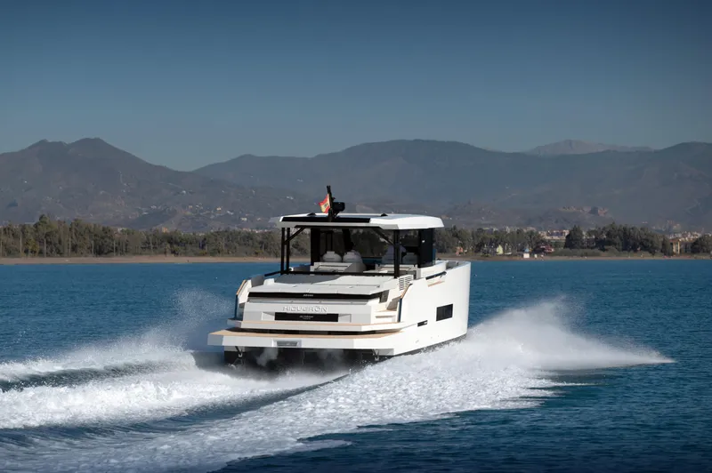 Slide: The Image of 2025 De Antonio Yachts D50 Coupé cruising on a serene lake with mountainous backdrop. - 2