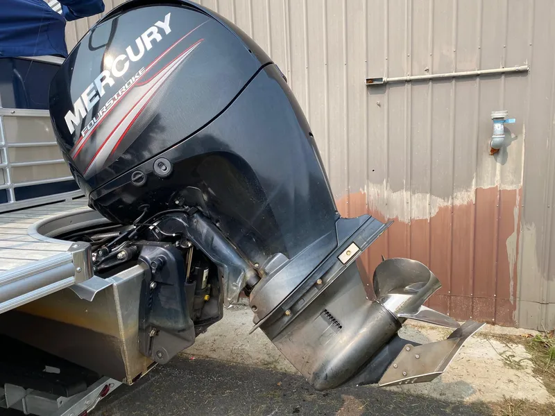 Slide: The Image of Mercury outboard motor on 2015 South Bay 724 E boat, docked near a metal building. - 12