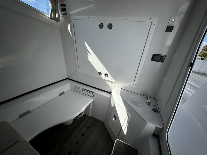 Slide: The Image of Interior of 2025 Sportsman Open 352 boat, featuring a compact bathroom with sink and storage. - 26