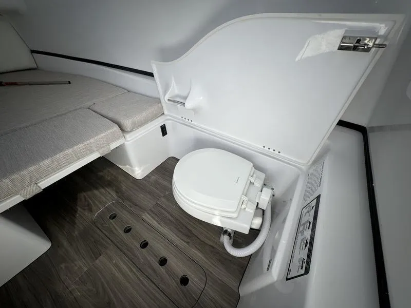 Slide: The Image of 2025 Sportsman Open 352 boat interior with compact marine toilet and seating area. - 28
